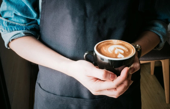 Image of a Barista holding a coffee